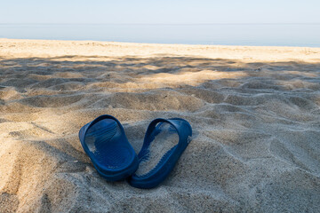 Fototapeta na wymiar Blue rubber slippers in the beach sand.