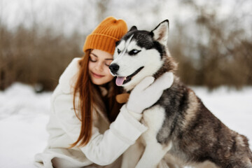 Happy young woman winter clothes walking the dog in the snow winter holidays