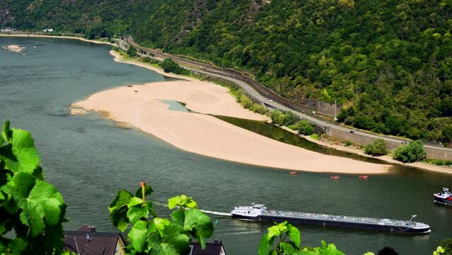 Ships and group of inflatable rafts navigating Rhine at low water near sandbank