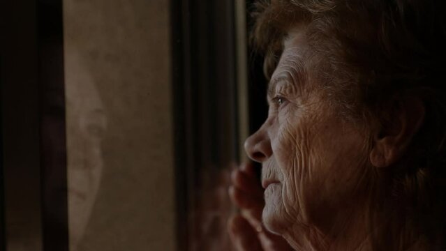 senior woman at home looking out the window