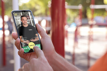 Man having workout with personal trainer via smartphone outdoors, closeup