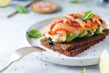 A rye bread sandwich with avocado and salmon
