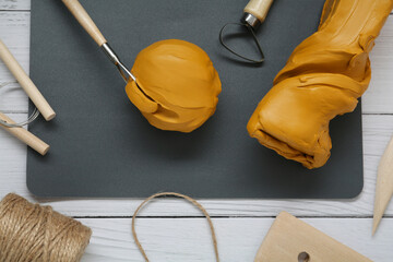 Clay and set of modeling tools on white wooden table, flat lay