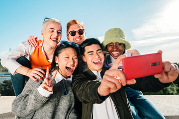 Group of multi-ethnic young friends taking a picture together with a smartphone.