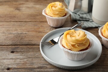Tasty cupcakes with cream served on wooden table. Space for text