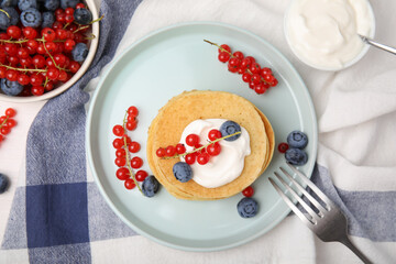 Tasty pancakes with natural yogurt, blueberries and red currants on table, flat lay