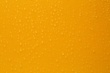 Water drops on orange background, top view