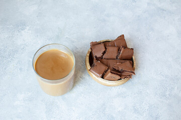 Glass of chocolate milk and chocolate in wooden bowl on background.Shot from above.
