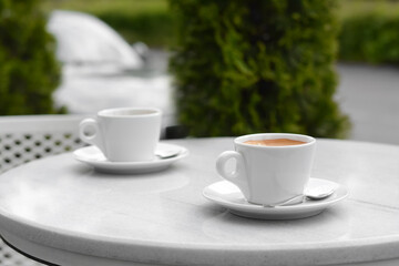 Ceramic cups of aromatic coffee with foam on table in morning