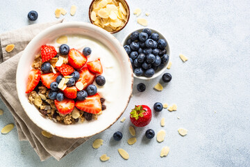 Greek Yogurt with granola and fresh berries at white stone table. Healthy dessert, snack or breakfast. Top view image.