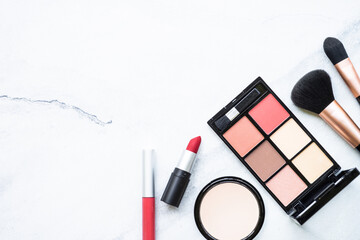 Makeup products, professional cosmetic on white marble background. Lipstick, powder, brushes. Flat lay image with copy space.