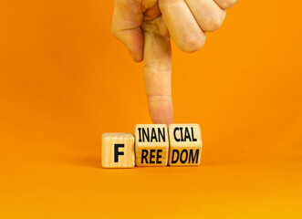Financial freedom symbol. Concept words Financial freedom on wooden cubes. Businessman hand. Beautiful orange table orange background. Financial freedom and business concept. Copy space.