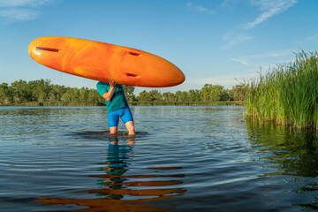 athletic, senior man is launching a prone kayak on a lake in Colorado, this water sport combines aspects of kayaking and swimming