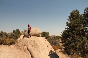 Filipina woman climbing down on sandstone boulder, Devil's Punchbowl Natural Area, Littlerock, California