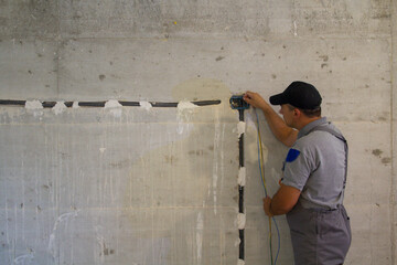 Image of a handyman electrician passing an electric probe through a corugate pipe on the construction site. Realization of an electrical system of a house. 