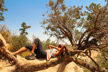 Filipina woman lying on lying tree, Devil's Punchbowl Natural Area, Littlerock, California