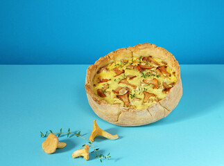 Freshly baked Quiche with chanterelle on blue background, copy space