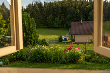 view through an old weathered vintage window to a picturesque green garden somewhere in the...