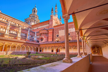 Visit small cloister of Certosa di Pavia monastery with huge Cathedral, Italy