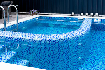 Swimming pool with blue tiles. Separate jacuzzi area. Relax in the backyard of a country house