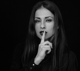Naklejka premium Serious business woman in black shirt gesture quiet sign in dark shadows. Closeup