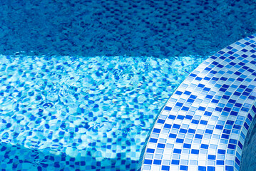 Swimming pool with blue tiles. In the rays of the sun. Relax in the backyard of a country house