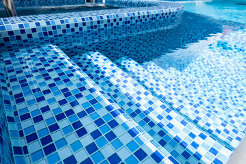 Steps in the pool with blue ceramic tile mosaic. Relax in the backyard of a country house