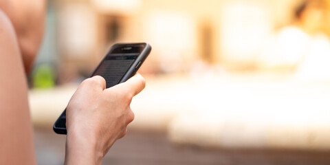 A woman holding the phone in her hand on a sunny summer day.