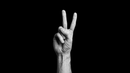 Hand making a victory sign, two fingers, showing two, on the black background, peace