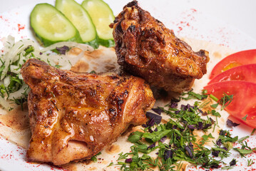 Pieces of fried chicken with vegetables on a white plate.