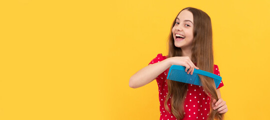 happy kid combing long hair. hairdresser. girl has wavy hairdo hold hairbrush. teen beauty...