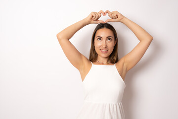 Fototapeta na wymiar Portrait of lovely charming brunette girl making love symbol heart figure with fingers over head looking up isolated on white background