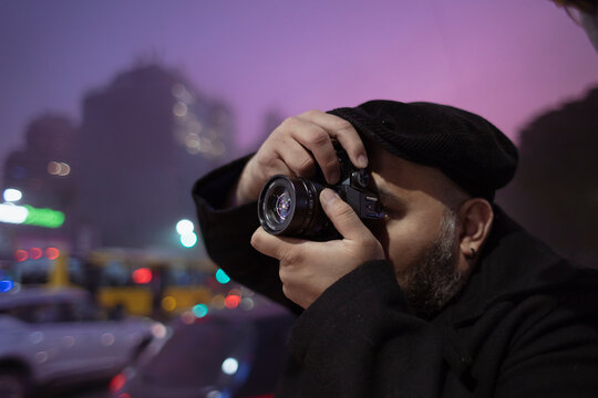 Fotógrafo callejero en la ciudad tomando fotos al atardecer con cámara vintage