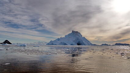 Small bits of ice floating in Cierva Cove, in front of a massive iceberg, Antarctica