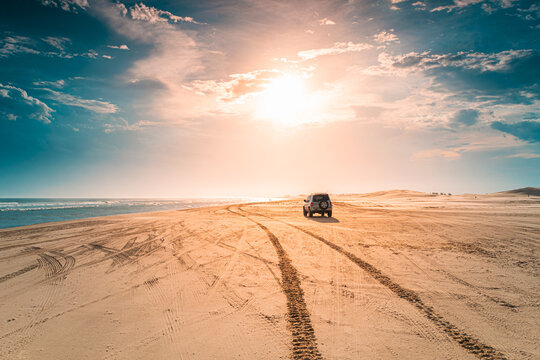 Sunset on the beach, with car tire tracks.