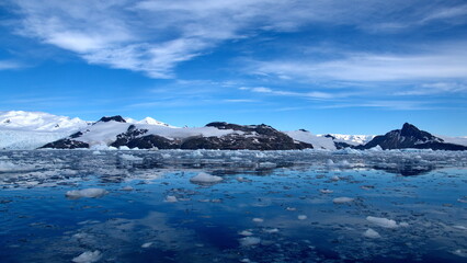 Small bits of ice floating in the bay in front of snow covered mountains at Cierva Cove, Antarctica