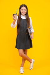 Teenager child with coffee cup isolated on yellow studio background. Girl drinking take away beverage.