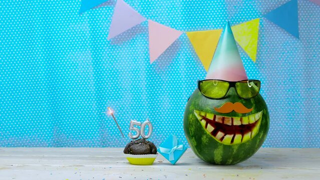 Creative birthday greeting copy space for two year old child. Video postcard happy birthday muffin with candles with number  50. Watermelon character in a comic smile holiday decorations