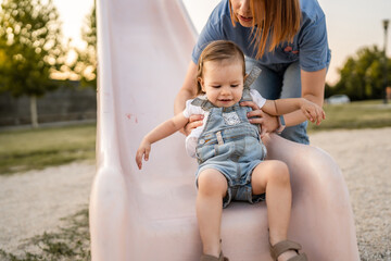 woman mother and daughter child on slide in park in summer day