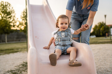 Fototapeta premium woman mother and daughter child on slide in park in summer day