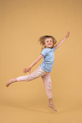 A joyful and happy little girl reaches up with her hand and jumps