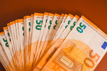  Money background.fifty euros banknotes set on a burgundy background.Spending and income in...