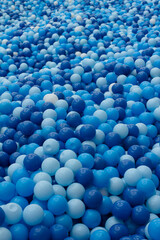 Vertical photo of a large number of plastic balls in a children's pool. Ball pool . Plastic balls in various shades of blue. Play