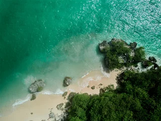 Poster Im Rahmen aerial drone view of padang padang beach in bali with waves, rocks and forest © JX