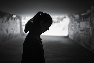 silhouette of a sad woman walking dark city streets alone 
