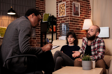 Husband and wife attending therapy consultation with counselor to solve relationship problems and conflict. Asking for professional advice from therapist at counseling session.
