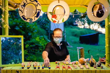 Latina woman artisan, arranging her products on a shelf in the street.