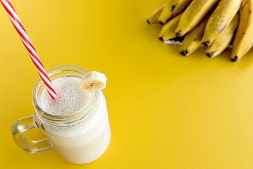 Banana smoothie cup, healthy shake with banana in the background.