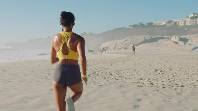Fitness, running and sports for a fit female sprinting on a beach shore during her morning training session. Sporty, fast and active woman doing cardio workout exercise outdoors from behind
