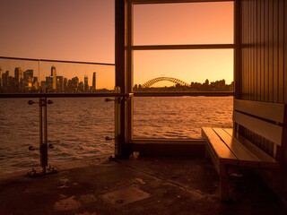 Cremorne Point Wharf at the waterfront with beautiful Sydney harbor sunset scenery in the background. Quiet romantic spot with a city skyline view.